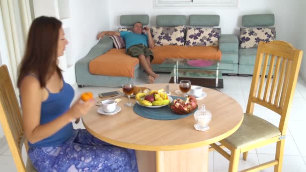 Пара їсть фрукти, сидячи на дивані вдома — стокове відео