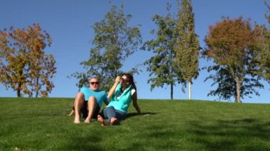 Kadın ve adam parkta yalınayak çimenlerin üzerine oturmuş dinleniyor