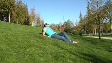 Parkta yalınayak yeşil çim üzerinde yalan istirahat kadın