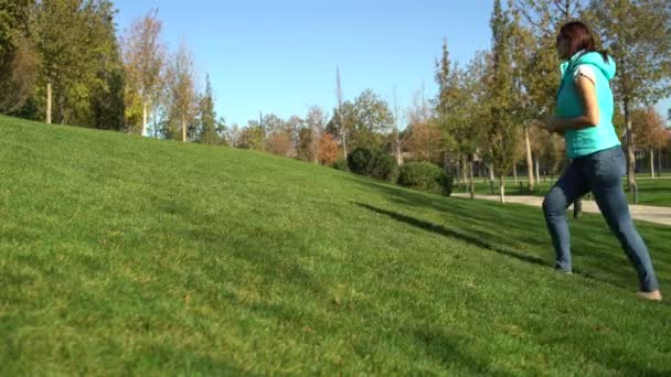 Mulher no parque sobe colina acima na grama verde descalça — Vídeo de Stock