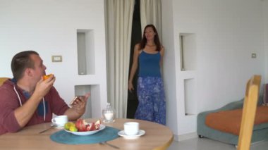 Bir adam bir akıllı telefon ile masada oturuyor. Bir kadın gelir ve bir sandalyeye oturur