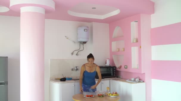 Woman cuts cucumber puts in a salad bowl and takes a tomato — Stock Video