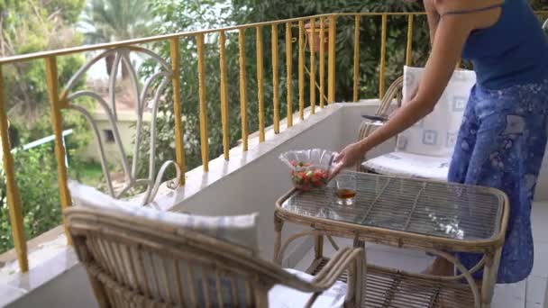 Vrouw zet een slaschaal met salade op tafel op het balkon — Stockvideo