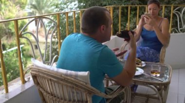 Bir adam elleriyle fırında patlıcan yiyor. Smartphone üzerinde fotoğraf çekimi kadın