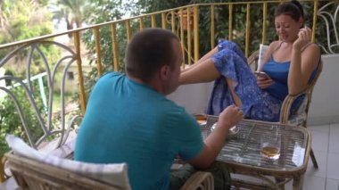 Bir erkek ve bir kadın bir balkonda oturan ve sigara. Bir adam bir sigara izmariti koyar