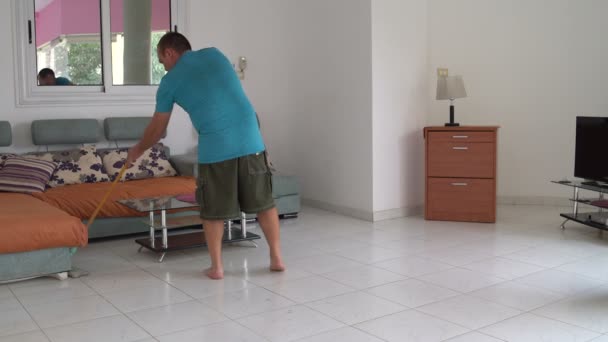 L'homme dans le salon lave le sol avec une serpillière — Video