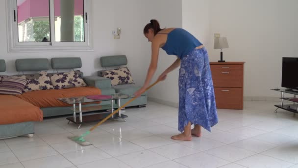 Vrouw in de woonkamer wast de vloer met een mop — Stockvideo