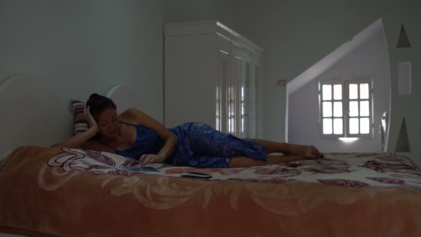 女性はベッドの寝室にある、タブレット pc を使用して. — ストック動画