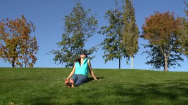 Yeşil çimenlerin üzerinde parkta yalınayak oturan kadın