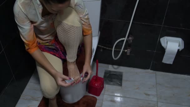 Женщина красит ногти на ногах в ванной комнате — стоковое видео