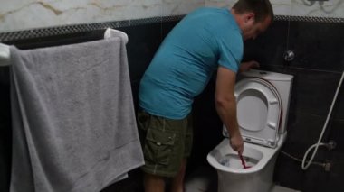 Adam tuvalette bir fırça kullanarak tuvalet yıkar