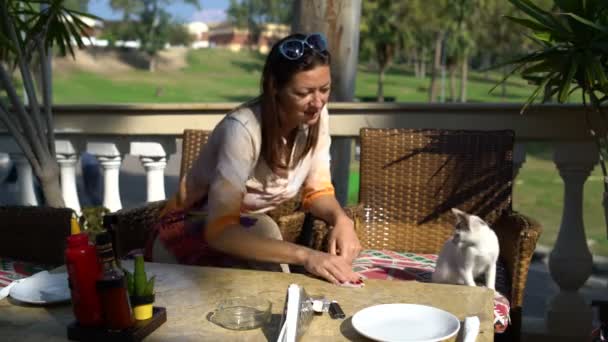 Une femme s'assoit dans un café et frotte la table avec une serviette — Video