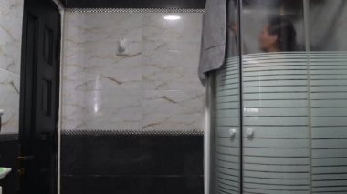 Duş kabini kadında bir havlu ile sildi