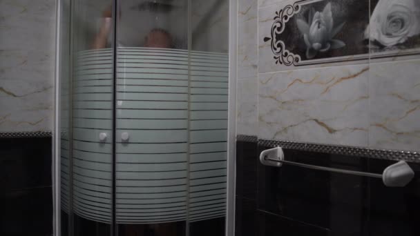 Un hombre se pone una toalla y sale de la cabina de ducha — Vídeo de stock