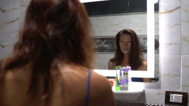 Kadın banyoda ayna önünde saç tarama