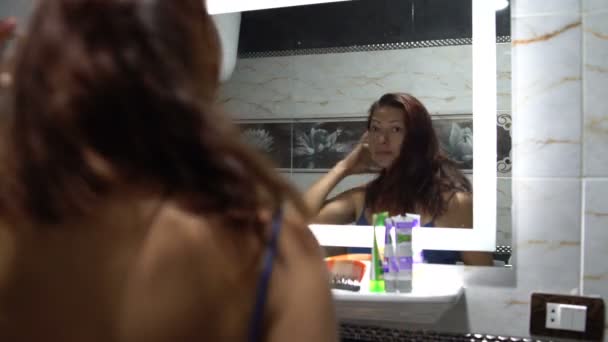 Vrouw kammen haar haar in de voorkant van een spiegel — Stockvideo