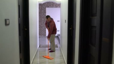 Bir adam koridorda bir paspas ile zemin yıkar