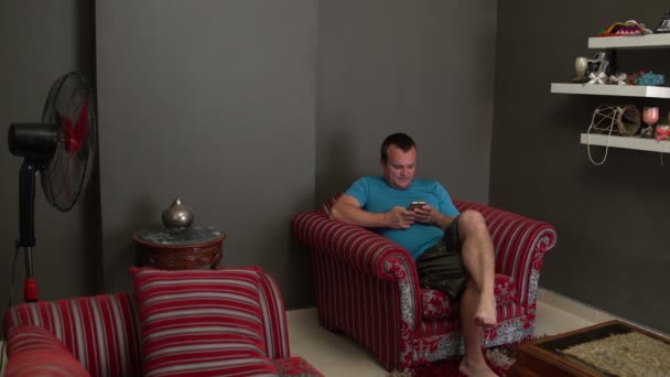 Un homme s'assoit sur une chaise et utilise un smartphone — Video