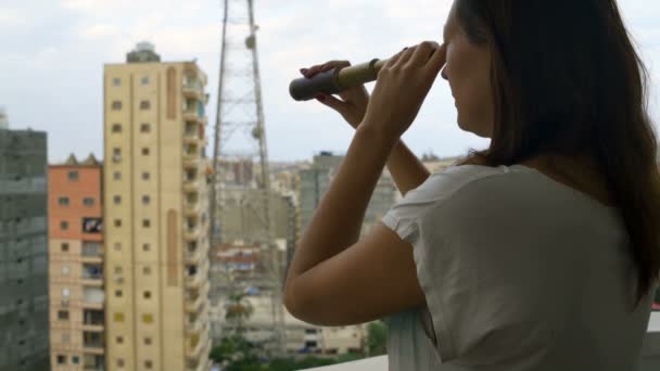 Frau betrachtet die Stadt durch ein Teleskop — Stockvideo