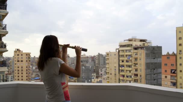 Woman looking through a telescope at the city — Stock Video