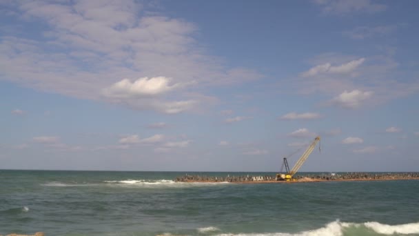 Bouw kraan staat in de zee op de landengte — Stockvideo