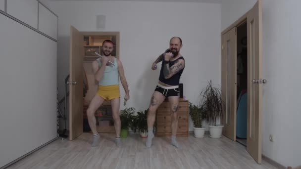 Zwei Männer in lächerlichen Klamotten treiben zu Hause Aerobic — Stockvideo