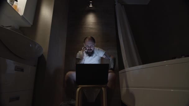 Ein Mann auf der Toilette bespricht die Arbeit am Telefon — Stockvideo