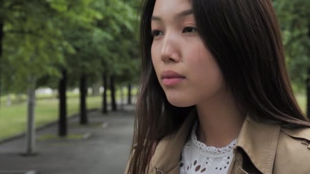 Una chica joven y hermosa se encuentra entre los árboles del parque Video de stock libre de derechos