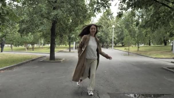 Uzun saçlı güzel bir kız ağaçlar boyunca bir ara sokakta koşuyor. — Stok video