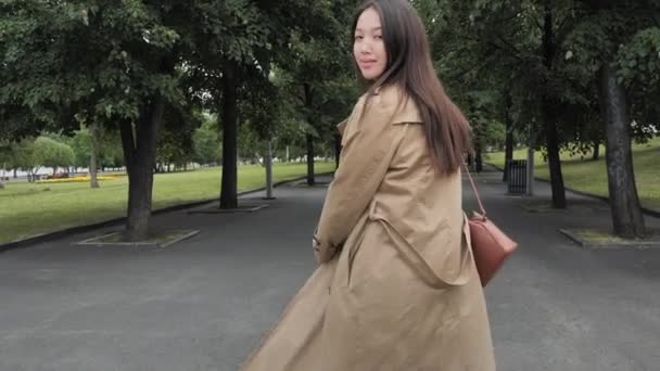 Asijské dívka hravě víří a narovnává si vlasy v parku — Stock video