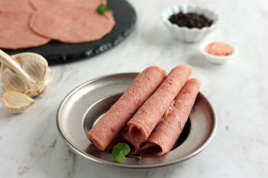 Tütsülenmiş biftek salamı, ince dilimlenmiş sosis ve mermer masa. 