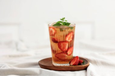 Glass of Strawberry Iced Tea Decorated with Fresh Mint and Sliced Strawberries