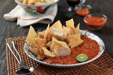 Close Up A Plate of Batagor or Baso Tahu Goreng with Spicy Peanut Sauce. Indonesian Traditional Street Food Fried Dumpling Made from Fish with Tapioca Flour, Tofu, and Dumpling Wrapper. 