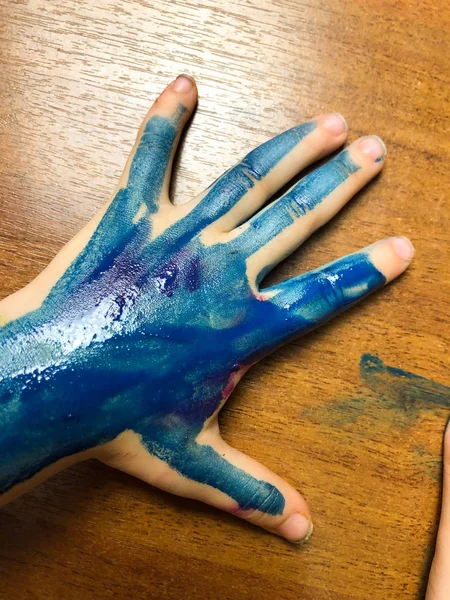 the child\'s hand while he paints. creative mess.