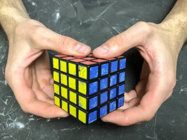 Rubik küpü 3 x 3 erkek eller, yakın çekim, üstten görünüm, mermer arka plan.