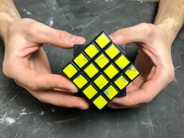 Rubik küpü 3 x 3 erkek eller, yakın çekim, üstten görünüm, mermer arka plan.