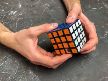 Rubik küpü 3 x 3 erkek eller, yakın çekim, üstten görünüm, mermer arka plan.