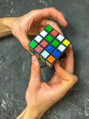 Rubik küpü 3 x 3 erkek eller, yakın çekim, üstten görünüm, mermer arka plan.