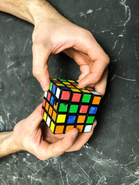 Rubik küpü 3 x 3 erkek eller, yakın çekim, üstten görünüm, mermer arka plan.