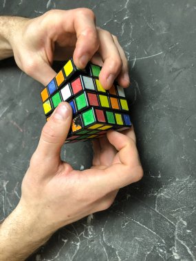 Rubik küpü 3 x 3 erkek eller, yakın çekim, üstten görünüm, mermer arka plan.