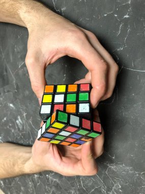 Rubik küpü 3 x 3 erkek eller, yakın çekim, üstten görünüm, mermer arka plan.