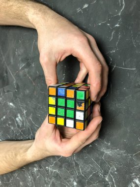 Rubik küpü 3 x 3 erkek eller, yakın çekim, üstten görünüm, mermer arka plan.