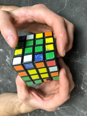 Rubik küpü 3 x 3 erkek eller, yakın çekim, üstten görünüm, mermer arka plan.