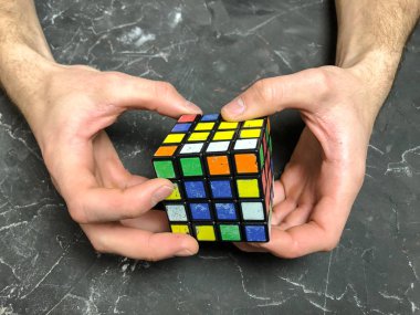 Rubik küpü 3 x 3 erkek eller, yakın çekim, üstten görünüm, mermer arka plan.