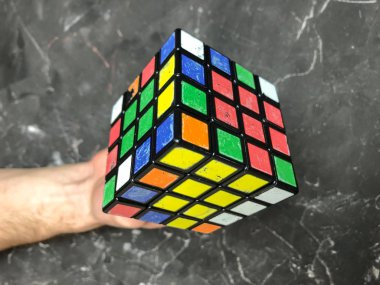 Rubik küpü 3 x 3 erkek eller, yakın çekim, üstten görünüm, mermer arka plan.