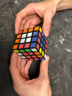 Rubik küpü 3 x 3 erkek eller, yakın çekim, üstten görünüm, mermer arka plan.