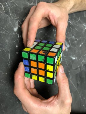 Rubik küpü 3 x 3 erkek eller, yakın çekim, üstten görünüm, mermer arka plan.
