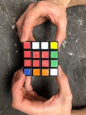 Rubik küpü 3 x 3 erkek eller, yakın çekim, üstten görünüm, mermer arka plan.