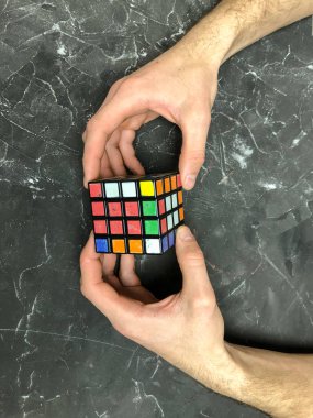 Rubik küpü 3 x 3 erkek eller, yakın çekim, üstten görünüm, mermer arka plan.