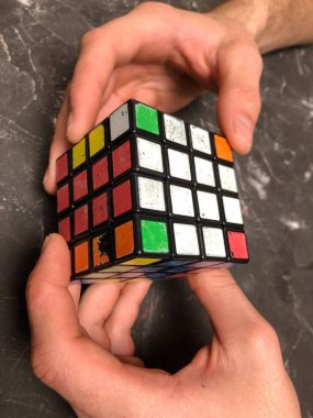 Rubik küpü 3 x 3 erkek eller, yakın çekim, üstten görünüm, mermer arka plan.